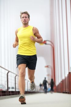 Fit runner running outside. Young male fitness model training in yellow on Golden Gate Bridge, San Francisco, California, USA.