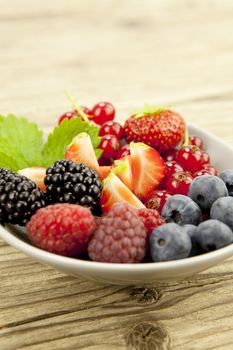 mixed fresh berries for dessert on wooden background in summer