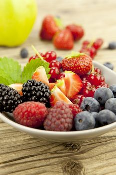 mixed fresh berries for dessert on wooden background in summer