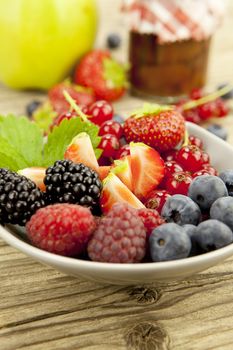 mixed fresh berries for dessert on wooden background in summer