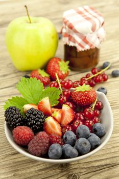 mixed fresh berries for dessert on wooden background in summer