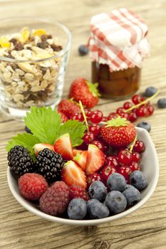 mixed fresh berries for dessert on wooden background in summer