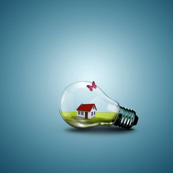 Electric light bulb and house inside it as symbol of green energy