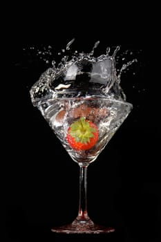 Falling strawberry in a glass with a drink                               