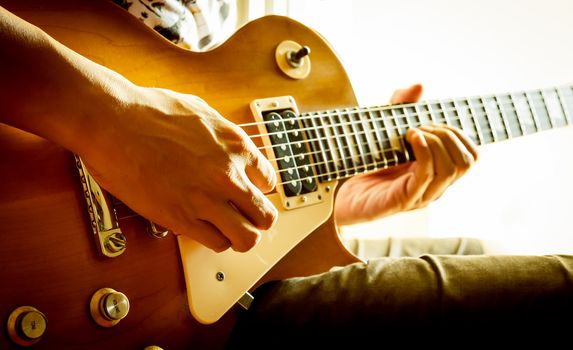 man playing electric guitar with nature light