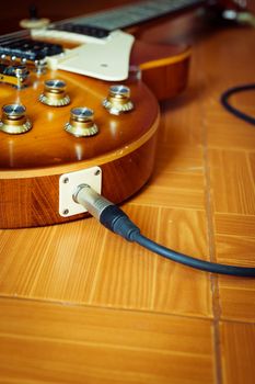 Electric guitar honey burst color on floor with jack cable