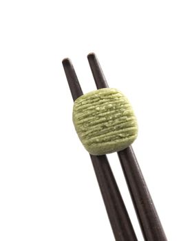close up of wasabi pellet on chopsticks