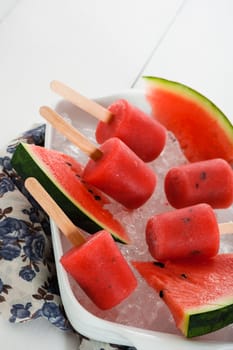 watermelon popsicle in a white bowl with ice and fresch watermelon