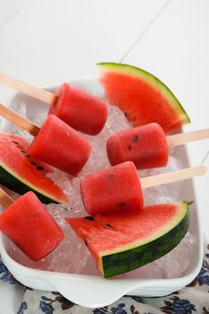 watermelon popsicle in a white bowl with ice and fresch watermelon
