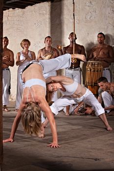 Pair of female capoeira practitioners performing with group