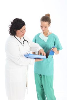 A female doctor and nurse in discussion over a patients notes as they stand looking at a folder together 