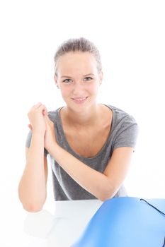 Young woman with a lovely smile sitting at a white table with a large blue folder in front of her Young woman with a lovely smile sitting at a white table with a large blue folder in front of her