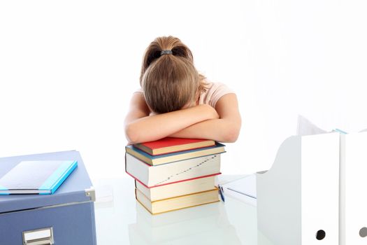 Young woman student seated at her desk asleep on a pile of books worn out by overwork and stress 