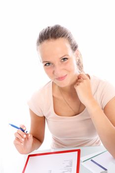 Smiling beautiful hardworking young female student sitting at her desk studying and making notes 
