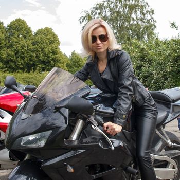 smiling biker girl dressed in leather clothes on a motorcycle