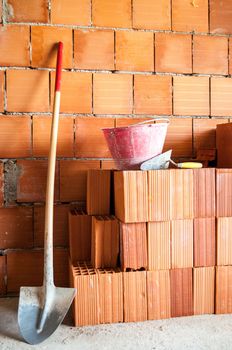 Masonry Brick wall with shovel, bucket and many bricks.