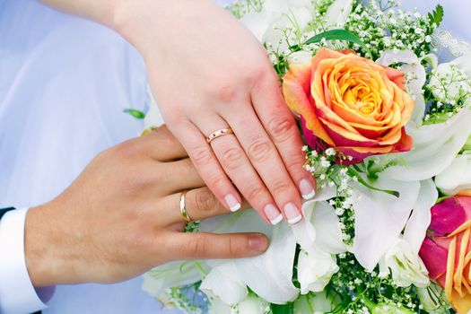 hands of the newlyweds and bridal bouquet