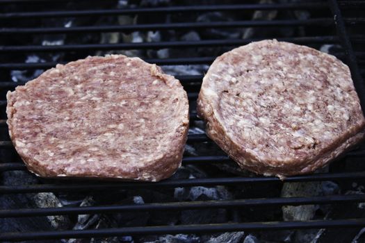 Raw hamburgers on the grill ready to be cooked.