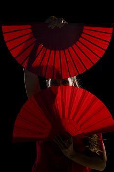 Flamenco dancer hiding behind her open folding fans
