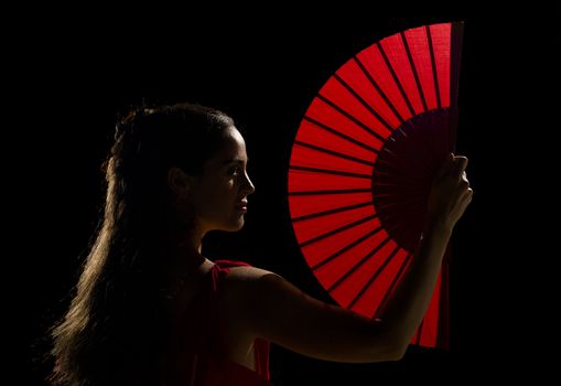 Female dancer holding a backlit red folding fan