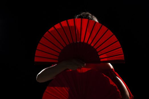 Female flamenco performer hidden behind her folding fans