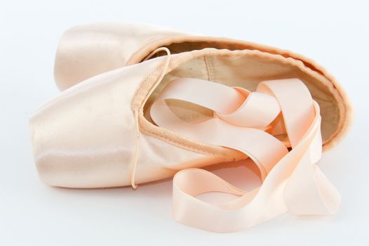 A pair light or pale pink ballet point shoes or slippers isolated on a white background with a lot of copyspace