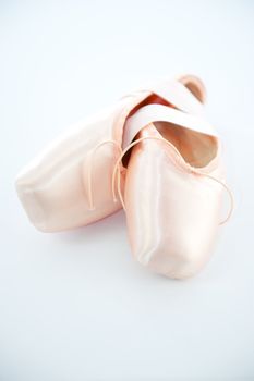 A pair light or pale pink ballet point shoes or slippers isolated on a white background with a lot of copyspace