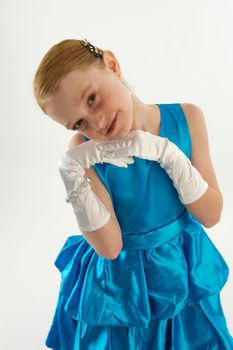 A young redheaded girl in a blue ball gown with white gloves and jewelry