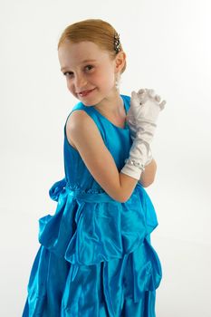 A young redheaded girl in a blue ball gown with white gloves and jewelry