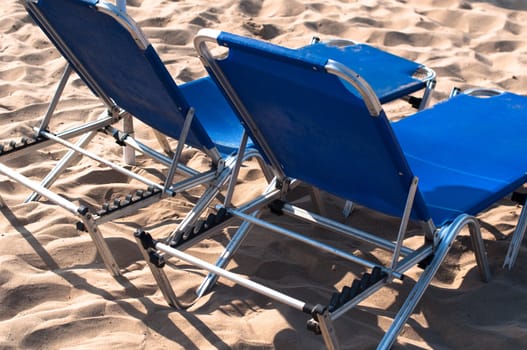 2 lonely blue sunbeds on sandy beach