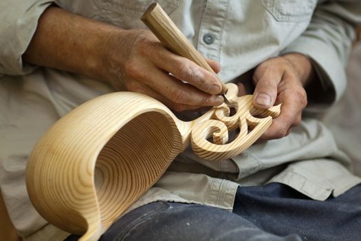 Master wood-carver made ​​using a special knife wooden national dish - a ladle with a patterned handle. A fragment of a close-up of his hands