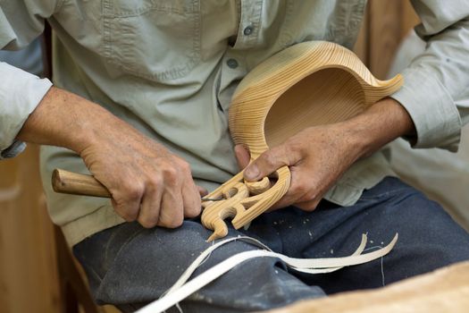 Master wood-carver made ​​using a special knife wooden national dish - a ladle with a patterned handle. A fragment of a close-up of his hands