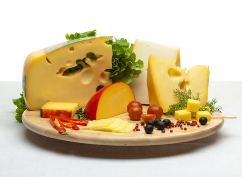 Composition of cheese on a wooden round tray on a white tablecloth, isolated on a white background