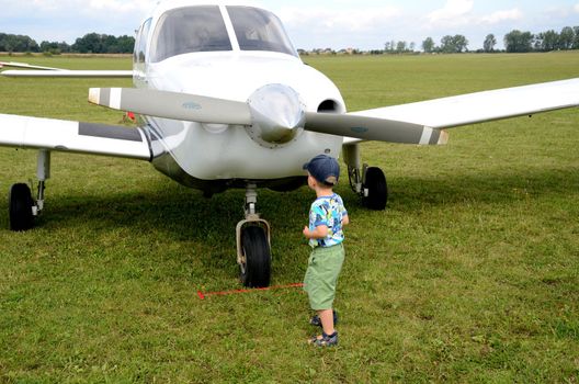 SZYMANOW, POLAND - AUGUST 25: Unidentified small boy approches Cessna plane during air show on August 25, 2012 in Szymanow.