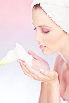 pretty woman with towel on head gently holding a white flower