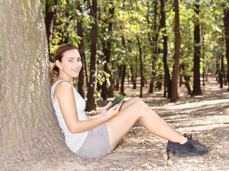 Girl in park on a sunny day with tablet computer