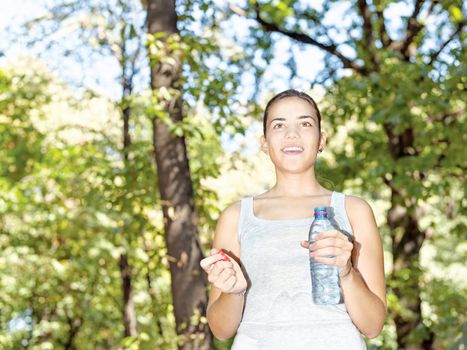 Happy girl in forest holding bottle of water