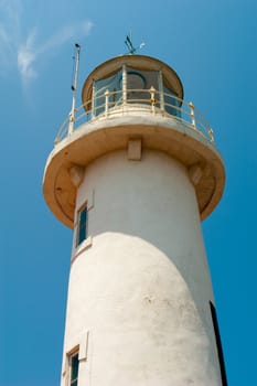 Marine white stone lighthouse in the sun against the blue sky