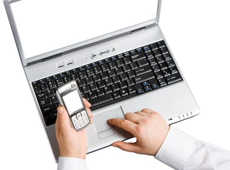 The young man in front of a laptop uses a mobile phone for Internet access. View from above