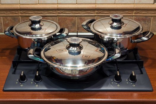 A set of cooking pots standing on kitchen stove