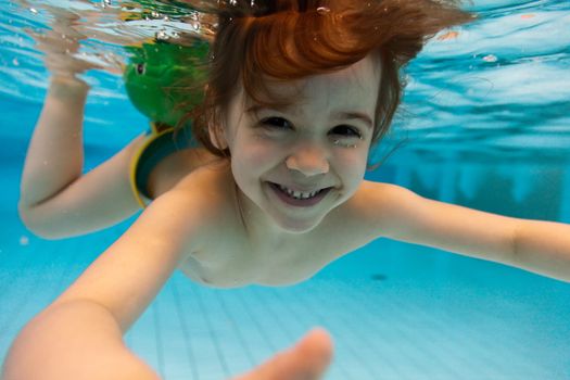 The little girl in the water park swimming underwater and smiling