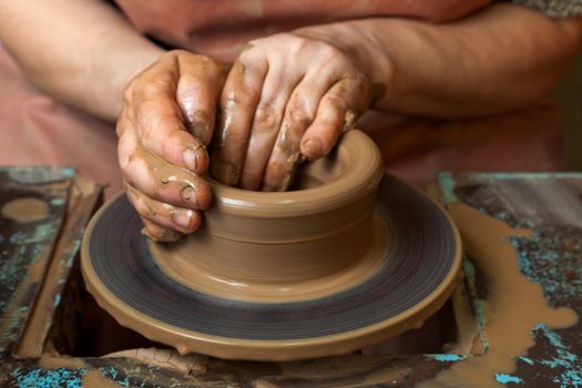 The hands of a potter, creating an earthen jar on the circle, close-ups