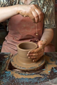 The hands of a potter, creating an earthen jar on the circle, close-ups