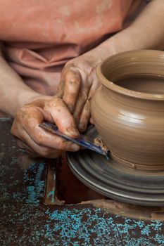 The hands of a potter, creating an earthen jar on the circle, close-ups