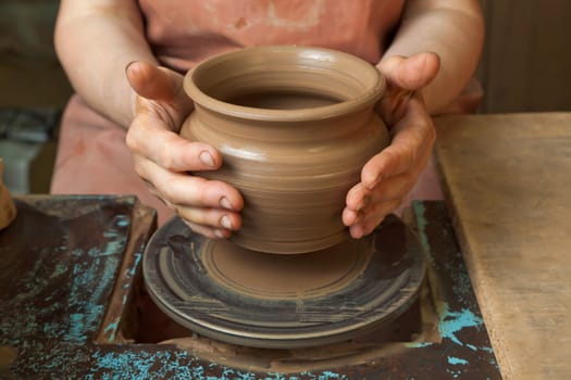 The hands of a potter, creating an earthen jar on the circle, close-ups