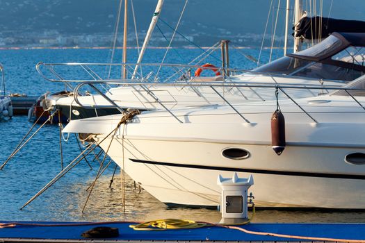 Two white yachts in the sea bay at anchor at the pier, lit the evening sun