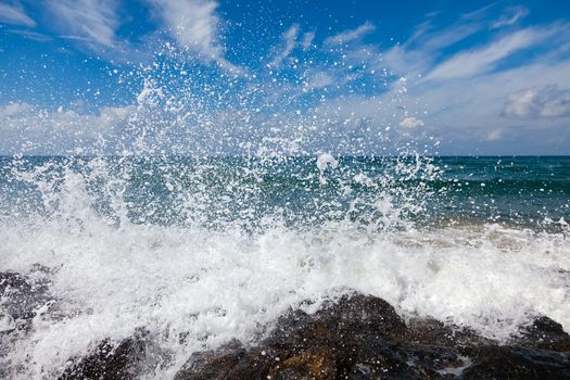 The waves breaking on a stony beach, forming a big spray