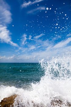 The waves breaking on a stony beach, forming a big spray