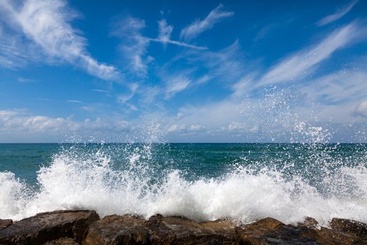 The waves breaking on a stony beach, forming a spray