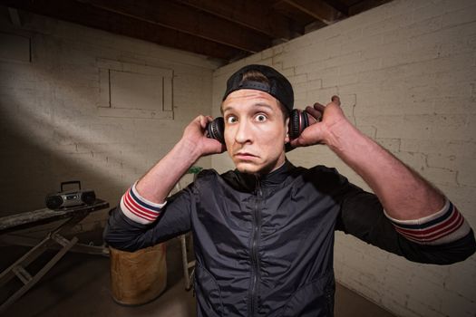 Surprised young man holding earphones over ears